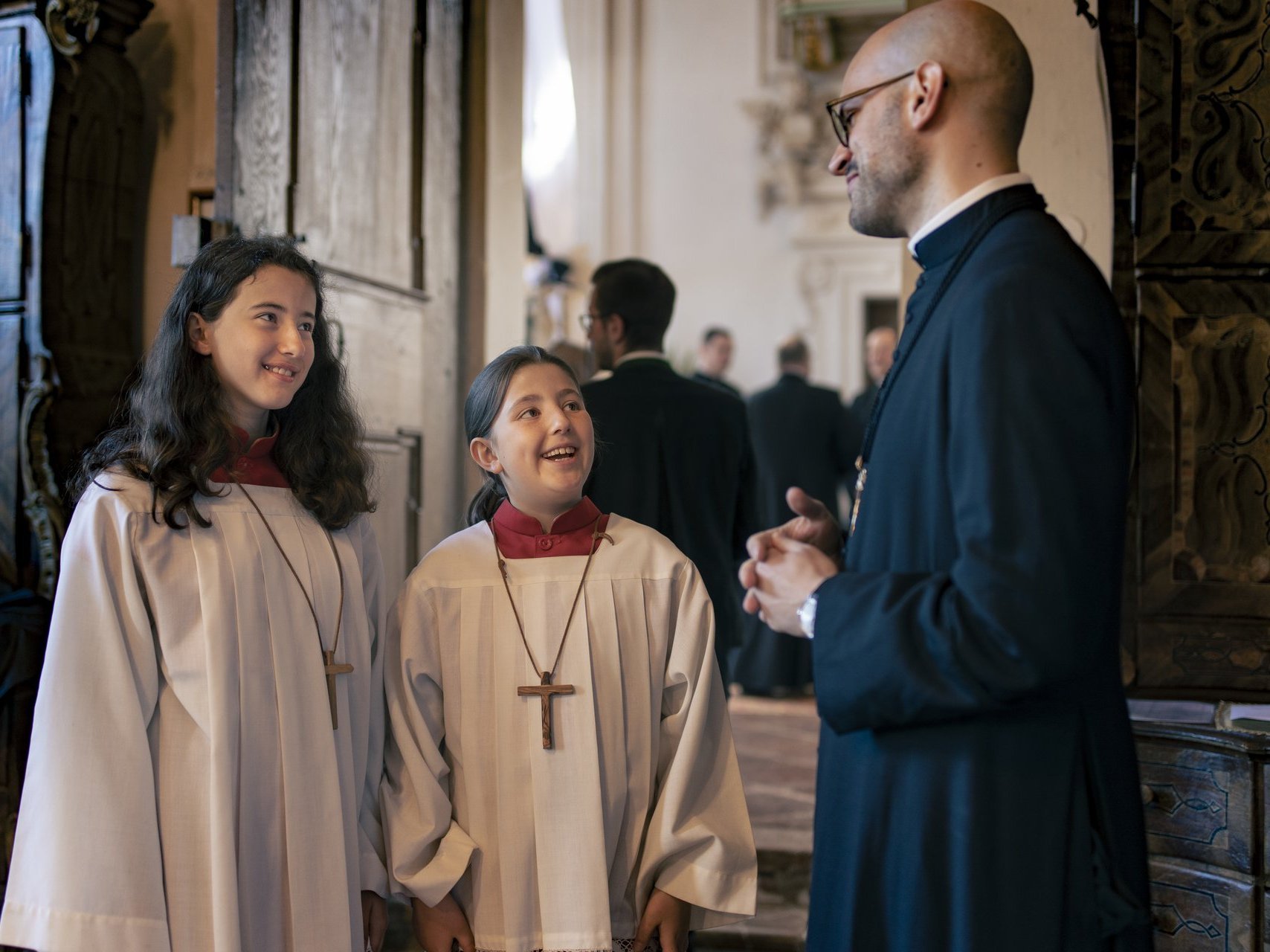 Zwei Ministrantinnen unterhalten sich mit einem Frater